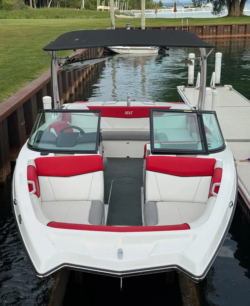 Slide: The Image of 2017 MasterCraft NXT22 boat docked, featuring red and white seating, with a black canopy. - 7
