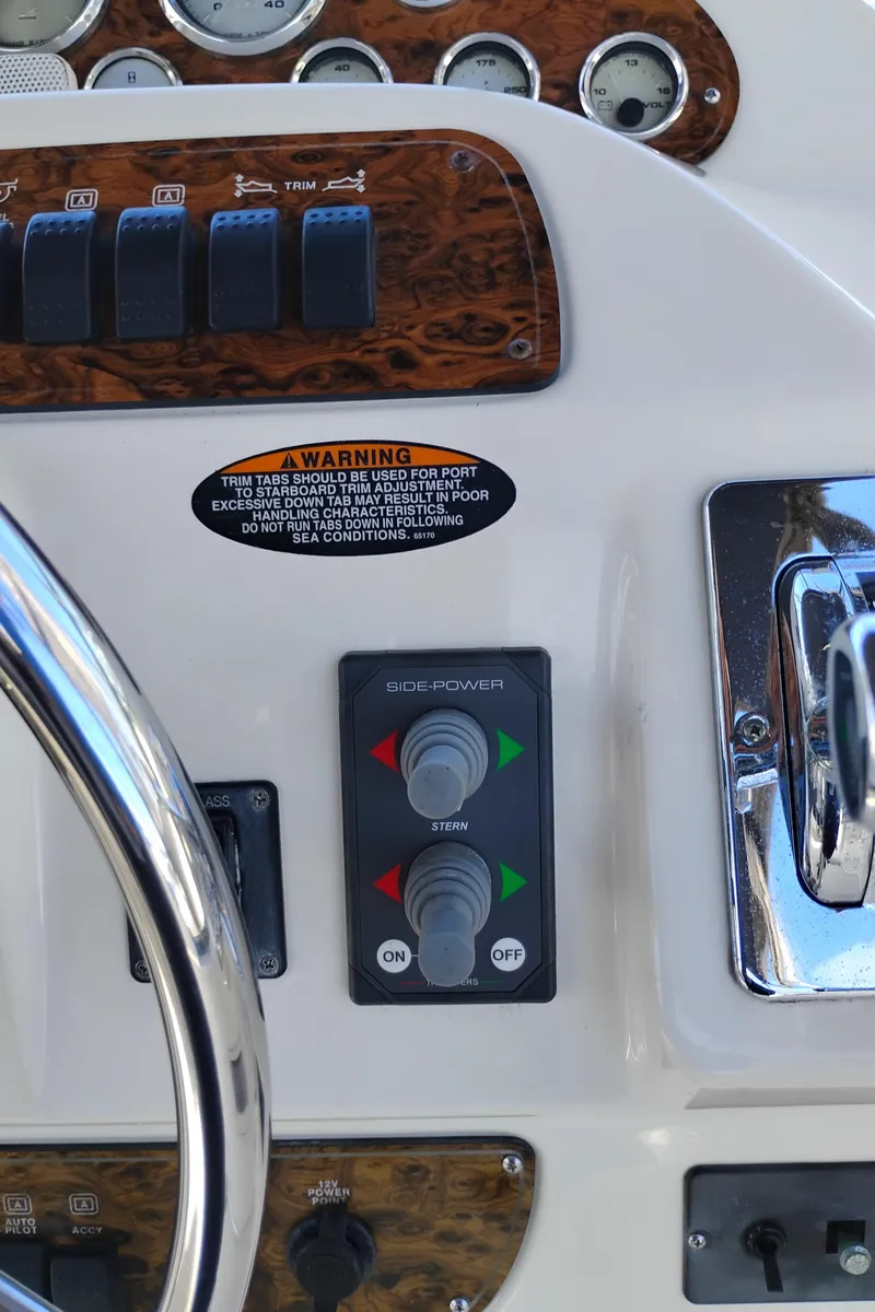 Slide: The Image of 2001 Bayliner 3488 Command Bridge Motoryacht helm controls with trim tabs and side-power switches. - 22