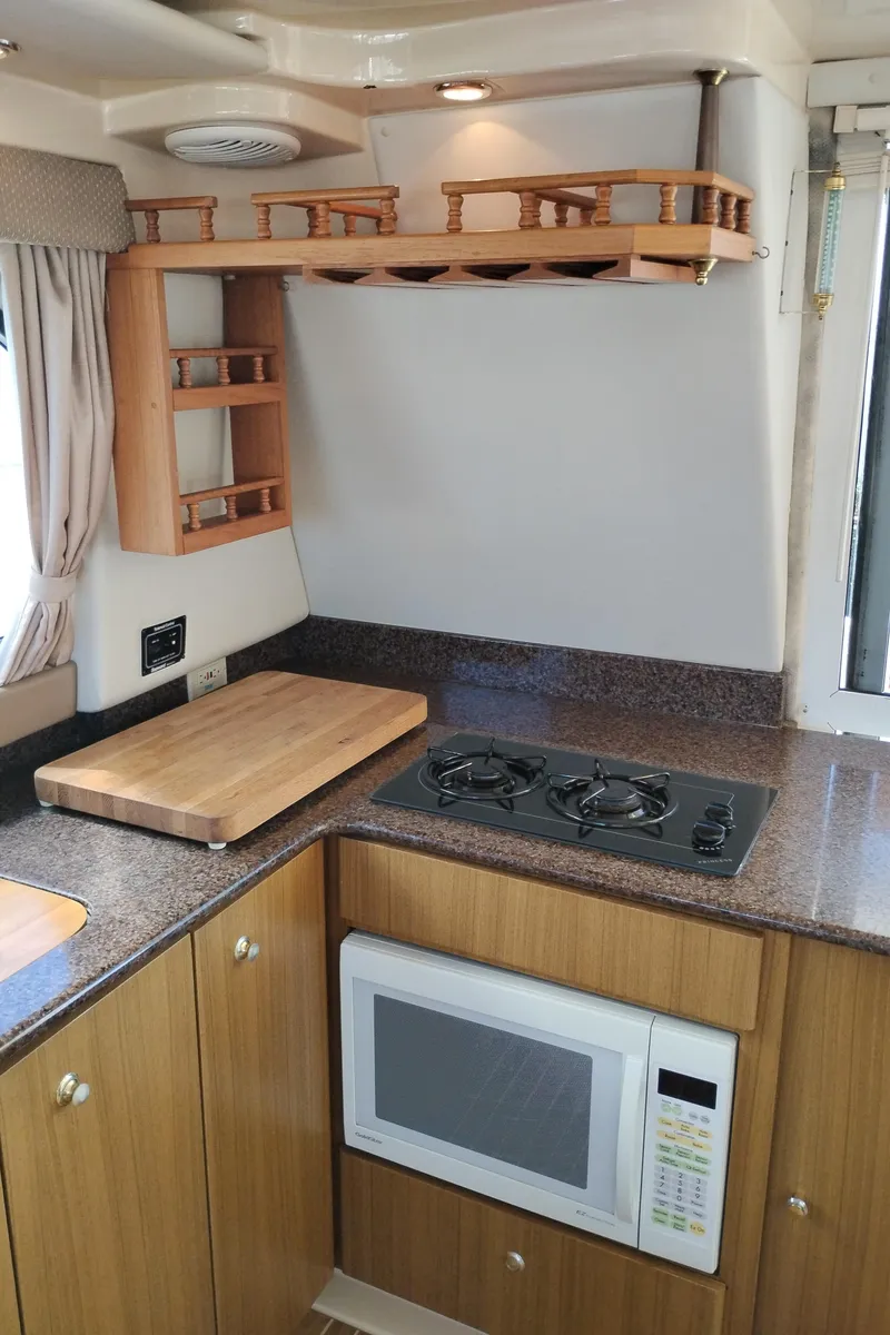 Slide: The Image of 2001 Bayliner 3488 Command Bridge Motoryacht kitchen with stove, microwave, and wooden cabinetry. - 29