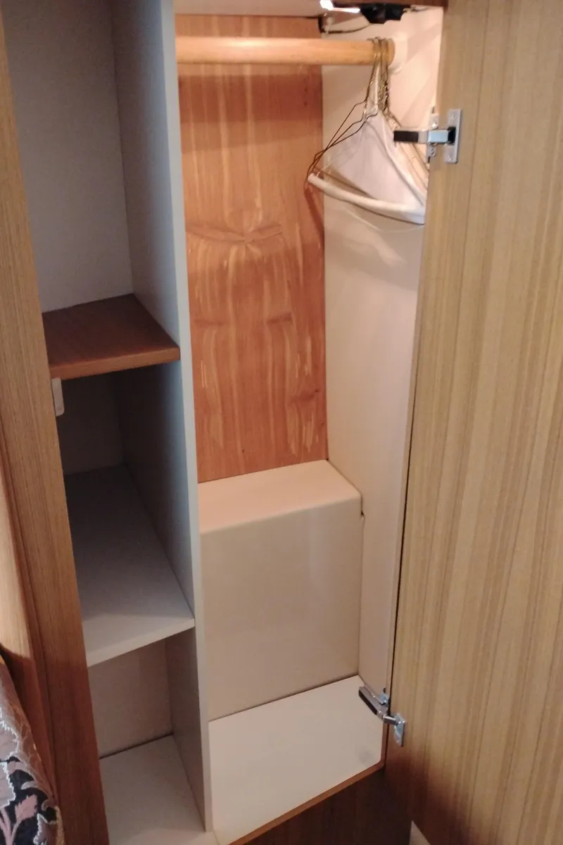 Slide: The Image of Wooden closet interior on 2001 Bayliner 3488 Command Bridge Motoryacht, featuring shelves and hangers. - 48