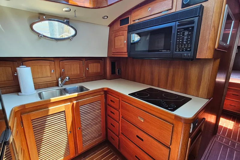 Slide: The Image of Luxurious 2005 San Juan 48 yacht kitchen with wood cabinetry, sink, stove, and microwave. - 61