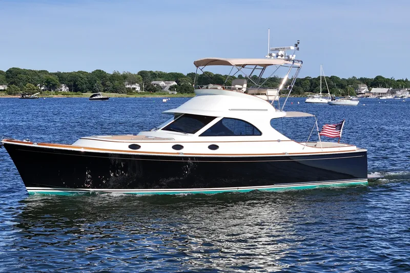 Slide: The Image of 2005 San Juan SJ 48 Flybridge yacht cruising on a scenic lake with American flag. - 7