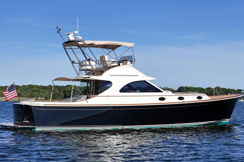 The Image of 2005 San Juan SJ 48 Flybridge yacht on calm water, showcasing sleek design and elegance. - 0