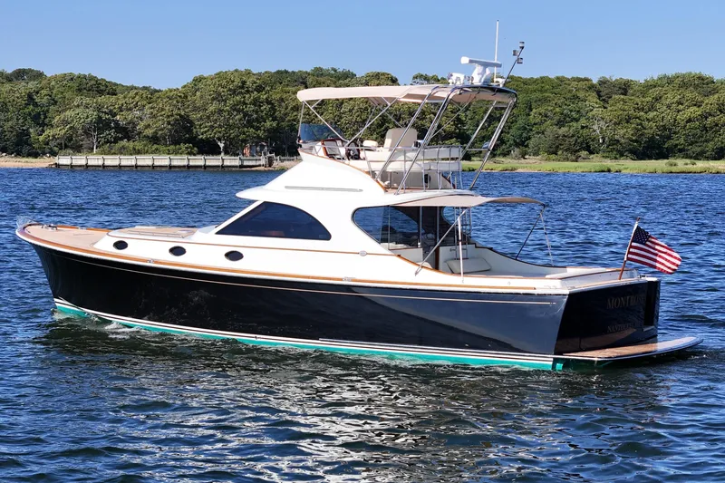 Slide: The Image of 2005 San Juan SJ 48 Flybridge yacht on water, featuring sleek design and American flag. - 8