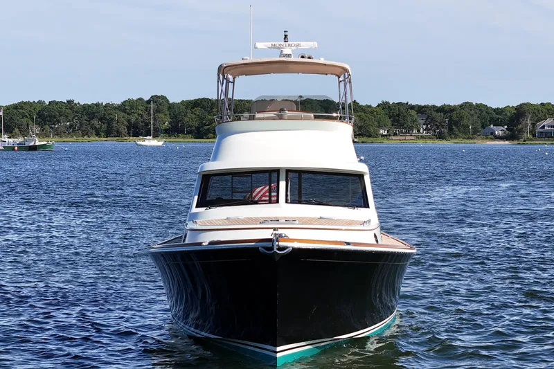 Slide: The Image of 2005 San Juan SJ 48 Flybridge yacht on calm water, surrounded by lush greenery. - 11