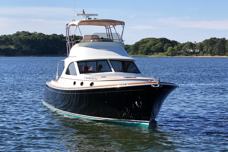 Slide: The Image of 2005 San Juan SJ 48 Flybridge yacht cruising on a serene lake with lush green shoreline. - 3