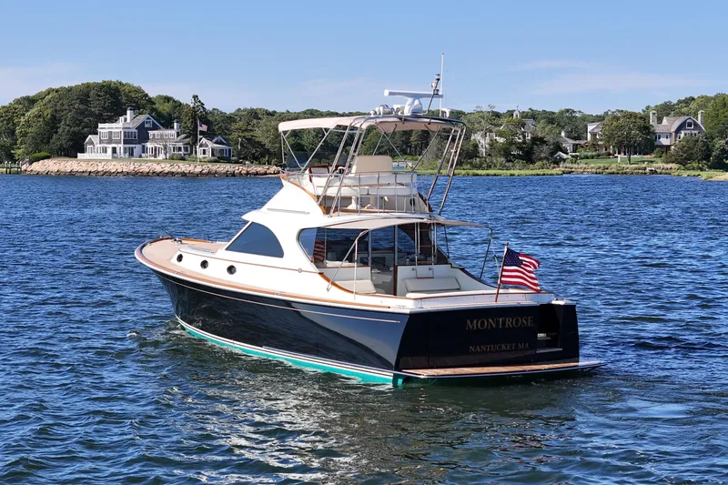 Slide: The Image of 2005 San Juan SJ 48 Flybridge yacht on water near coastal homes. - 9