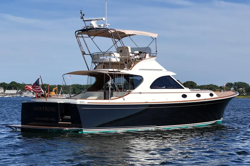 Slide: The Image of 2005 San Juan SJ 48 Flybridge yacht on water, featuring elegant design and American flag. - 2