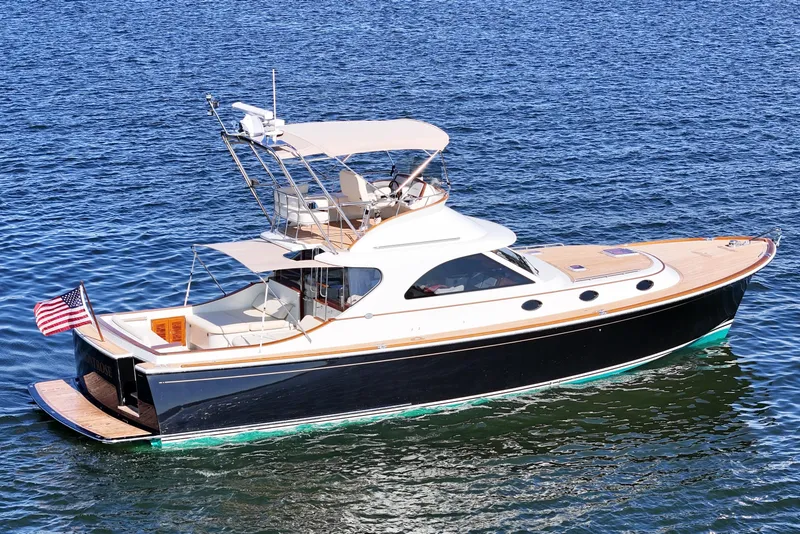 Slide: The Image of 2005 San Juan SJ 48 Flybridge yacht on calm blue water, featuring elegant design and American flag. - 4
