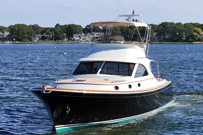 Slide: The Image of 2005 San Juan SJ 48 Flybridge yacht cruising on a scenic lake with waterfront homes. - 20