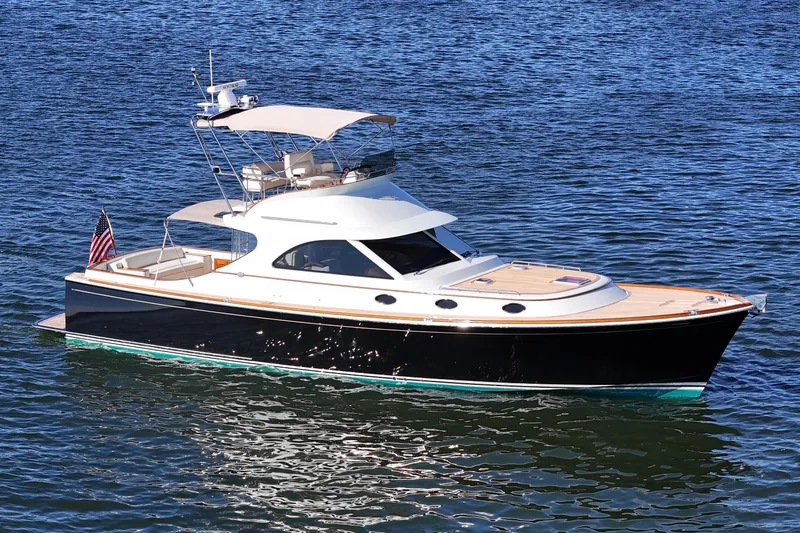 Slide: The Image of 2005 San Juan SJ 48 Flybridge yacht on calm water, featuring sleek design and American flag. - 10