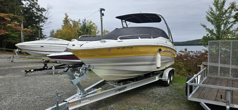 The Image of 2007 Crownline 260 LS boat on trailer, yellow and white, parked near a lake. - 1