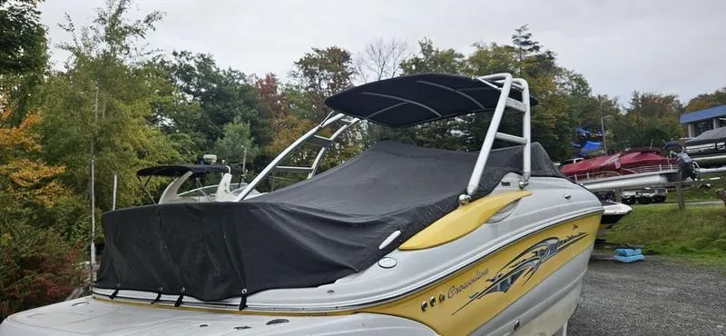 Slide: The Image of 2007 Crownline 260 LS boat with cover, parked outdoors near trees and other boats. - 3