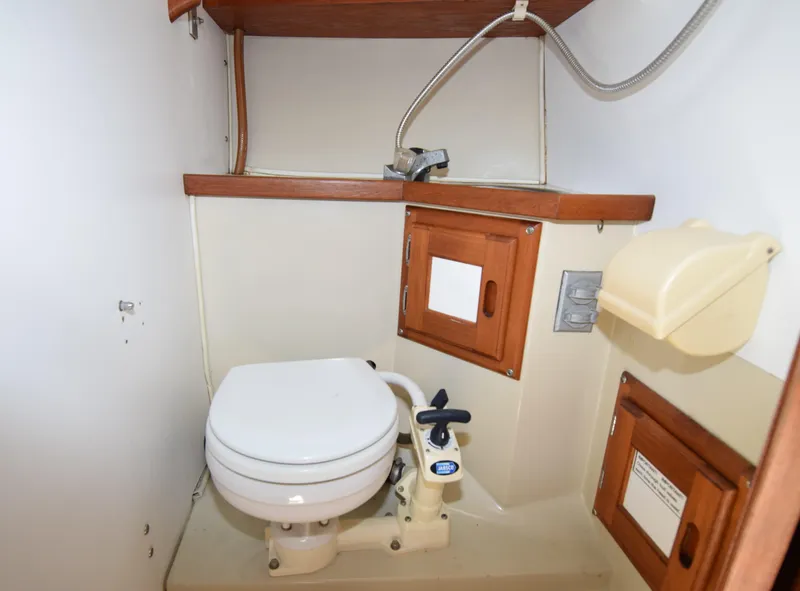 Slide: The Image of 1984 Catalina 30 boat bathroom with toilet, wooden cabinets, and sink. - 7