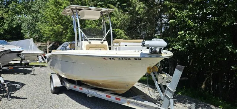 Slide: The Image of 2016 Scout 195 Sportfish boat on trailer, parked outdoors, surrounded by trees. - 1