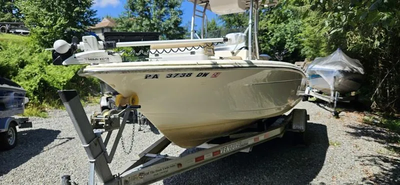 Slide: The Image of 2016 Scout 195 Sportfish boat on trailer, parked outdoors, surrounded by trees and other boats. - 2