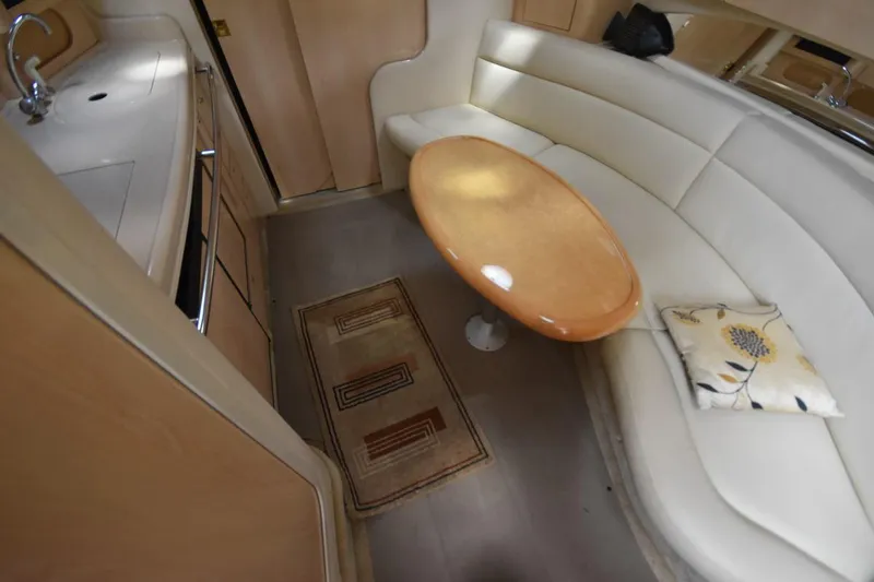 Slide: The Image of 2003 Sea Ray 360 Sundancer interior with curved seating, wooden table, and kitchenette. - 31