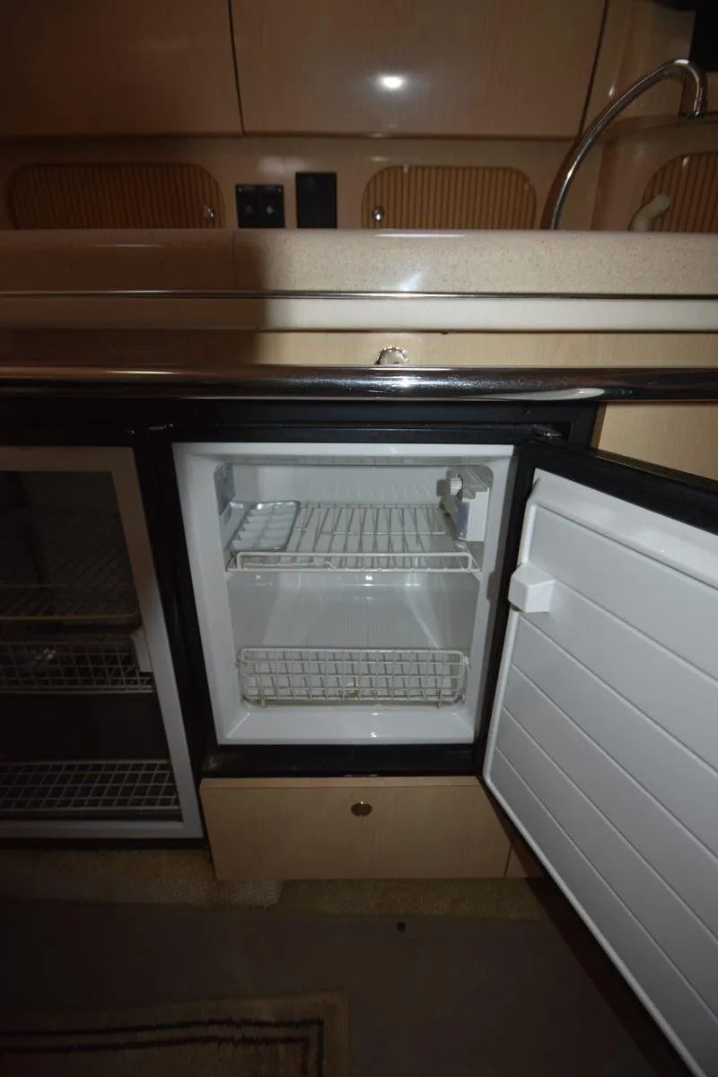 Slide: The Image of 2003 Sea Ray 360 Sundancer interior with open mini fridge in the kitchen area. - 33