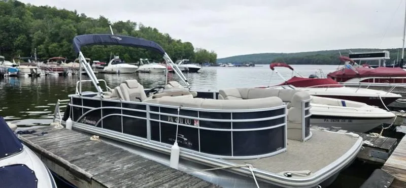 The Image of 2018 Bennington 22 SCWX pontoon boat docked at a scenic lakeside marina. - 1