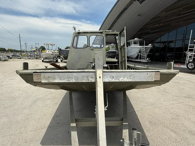 Slide: The Image of 1995 Custom Aluminum 2073 Cabin boat on trailer, parked outdoors near modern building. - 2