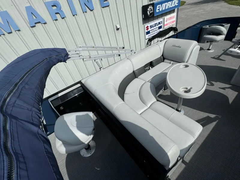 Slide: The Image of 2021 Bentley Pontoons 243 FISH 4PT with seating and table, displayed at a marine dealership. - 10