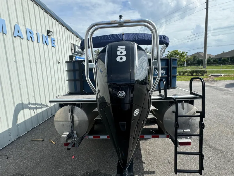 Slide: The Image of 2021 Bentley Pontoons 243 FISH 4PT with powerful outboard motor, parked near marine facility. - 15