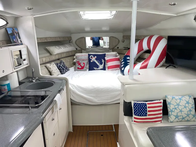 Slide: The Image of 2002 Wellcraft 330 Coastal cabin interior with nautical decor and American flag-themed pillows. - 10