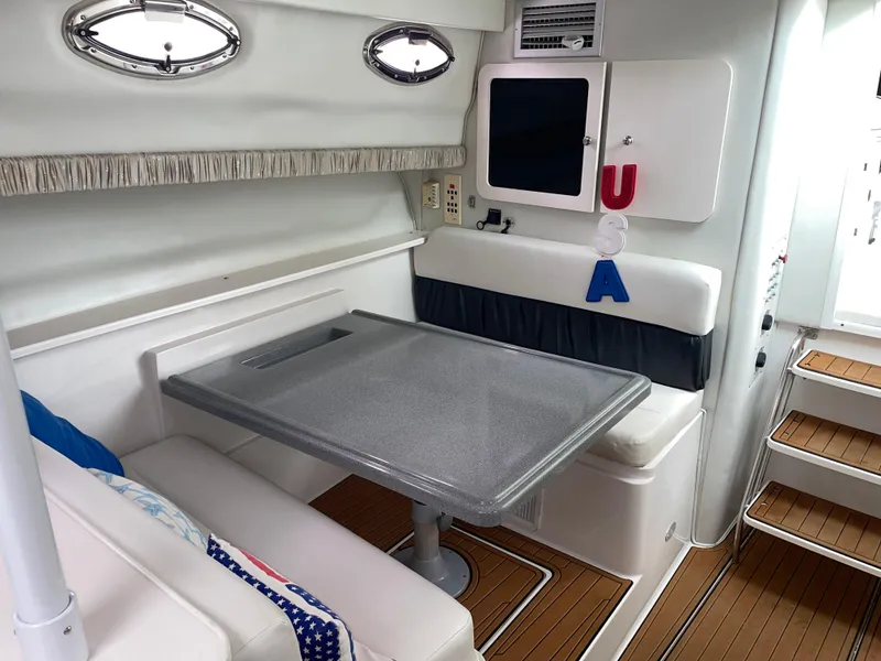 Slide: The Image of 2002 Wellcraft 330 Coastal cabin interior with table, seating, and USA decor. - 11