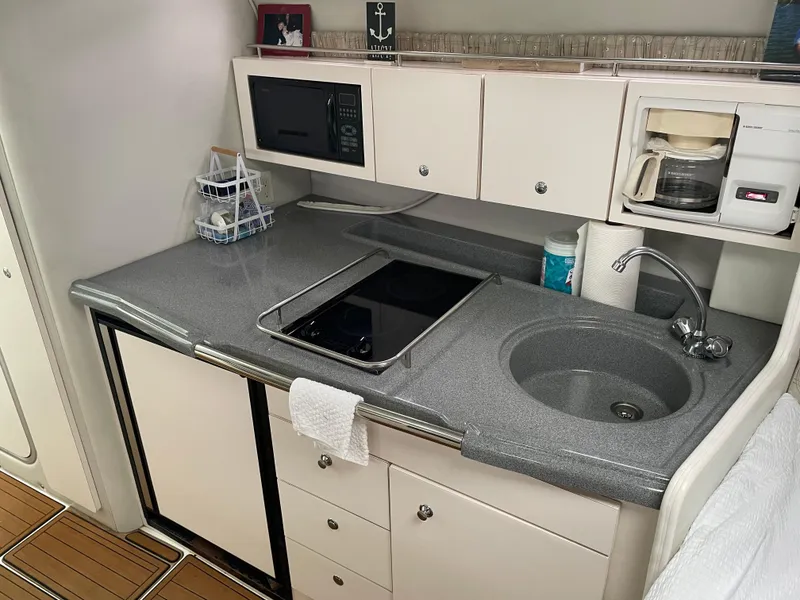 Slide: The Image of 2002 Wellcraft 330 Coastal boat kitchen with sink, stove, microwave, and coffee maker. - 13