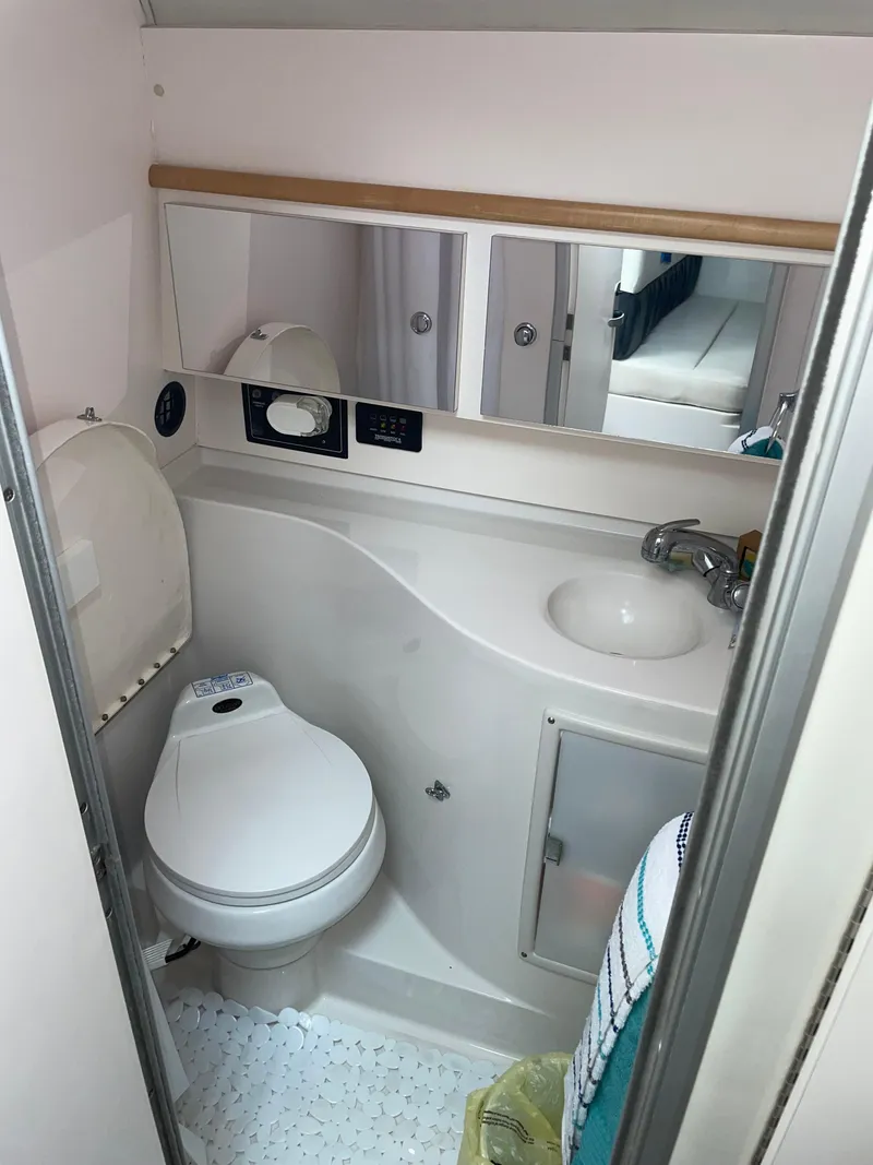 Slide: The Image of Compact bathroom in a 2002 Wellcraft 330 Coastal boat, featuring a toilet and sink. - 14