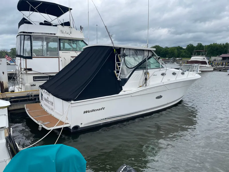 Slide: The Image of 2002 Wellcraft 330 Coastal boat docked in a marina, featuring a black canopy. - 2