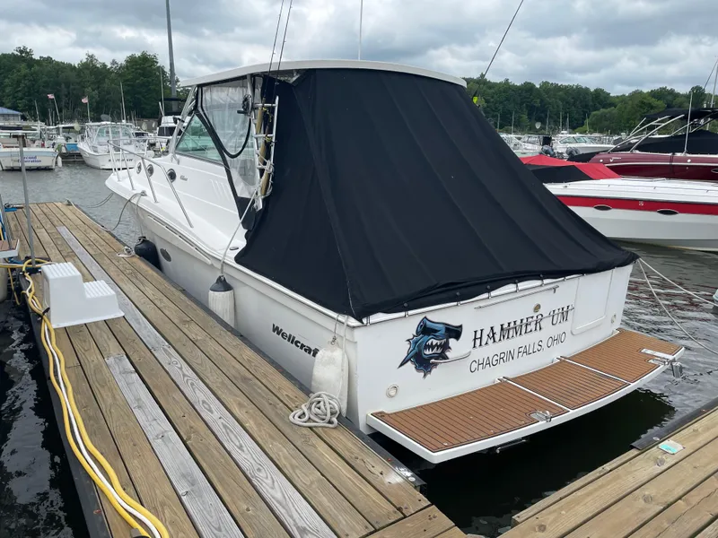 Slide: The Image of 2002 Wellcraft 330 Coastal boat docked at marina, covered with black tarp. - 3