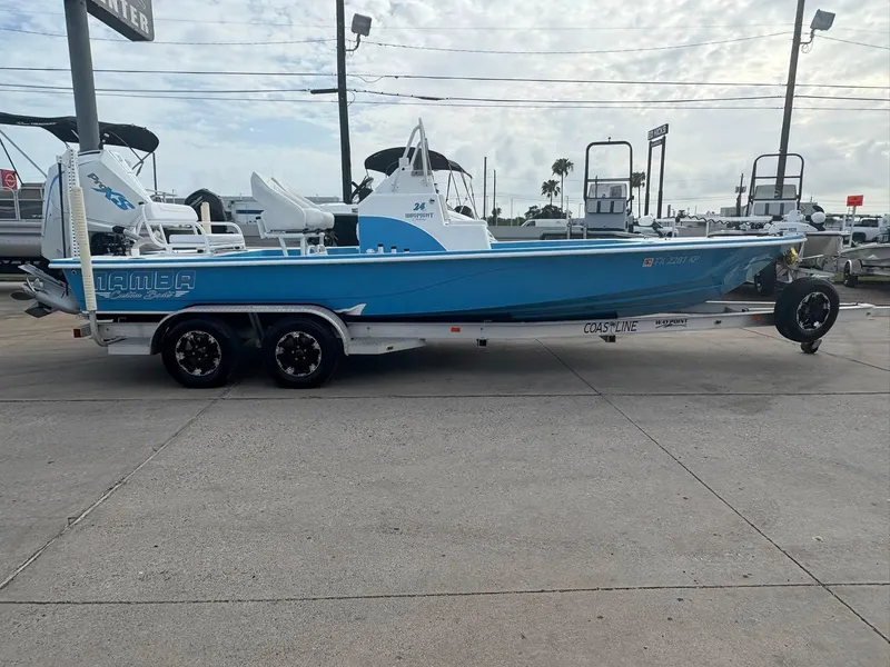Slide: The Image of 2022 Mamba 24VX boat on trailer, blue and white design, parked outdoors. - 1