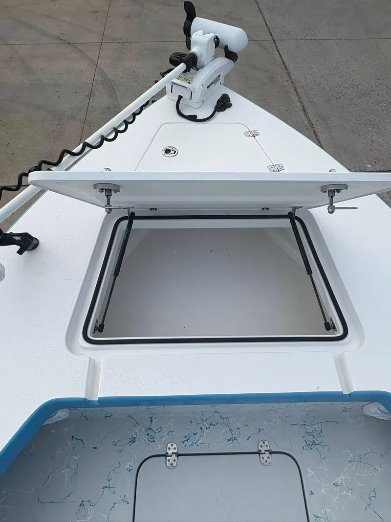 Slide: The Image of Open storage compartment on 2022 Mamba 24VX boat deck, featuring a trolling motor. - 12