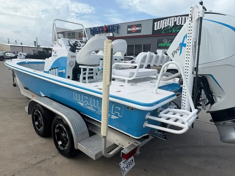 Slide: The Image of Blue 2022 Mamba 24VX boat on trailer, parked outside dealership. - 2