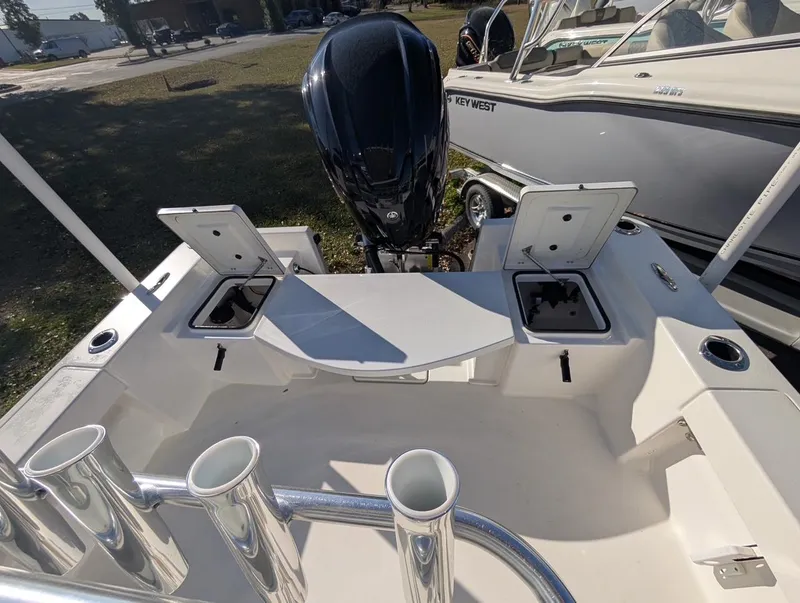 Slide: The Image of 2025 Bay Rider 239 Bay boat with open storage compartments and motor, parked outdoors. - 10