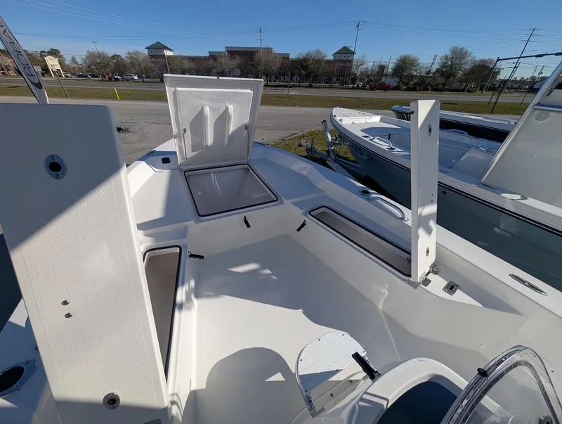 Slide: The Image of 2025 Bay Rider 239 Bay boat interior with open storage compartments, parked outdoors. - 11