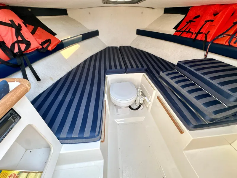 Slide: The Image of 2001 Pursuit 2460 Denali cabin interior with striped cushions and life jackets. - 11