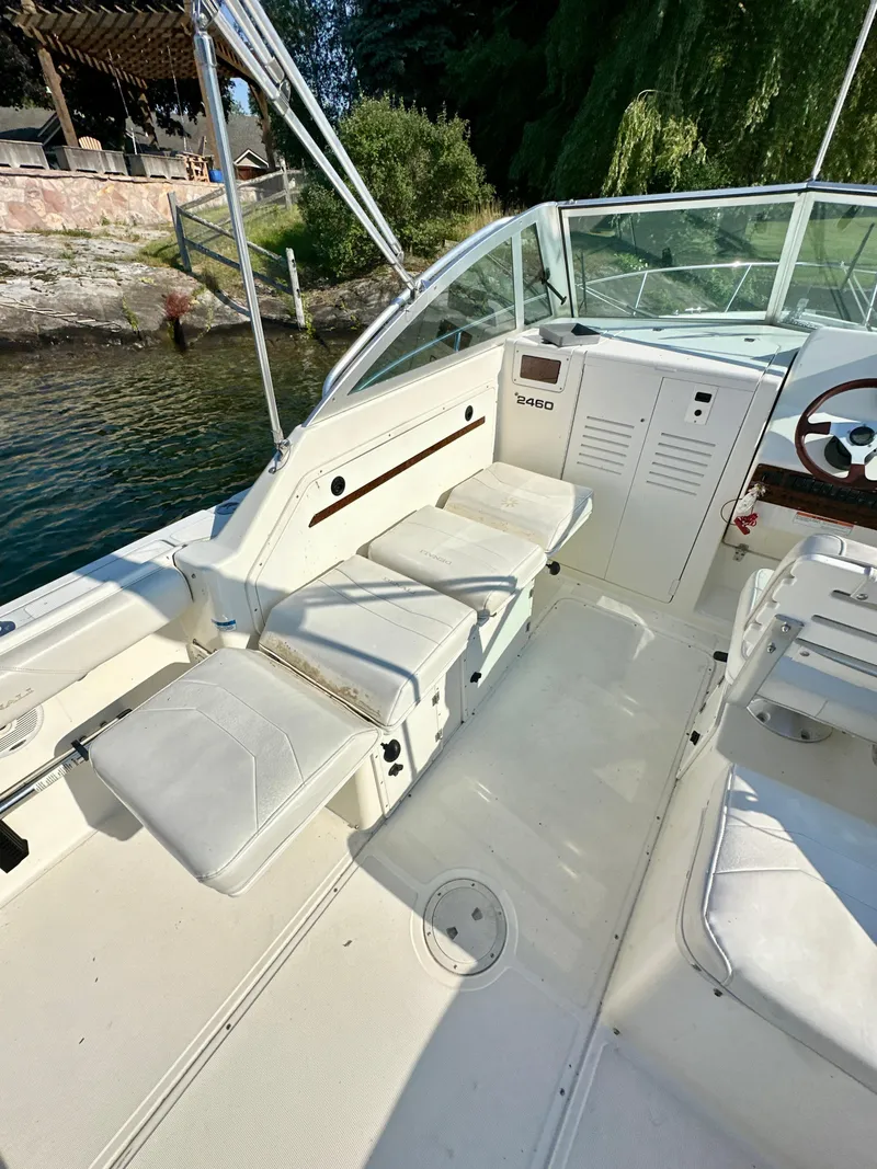 Slide: The Image of 2001 Pursuit 2460 Denali boat interior with white seating and steering wheel, docked by the water. - 7