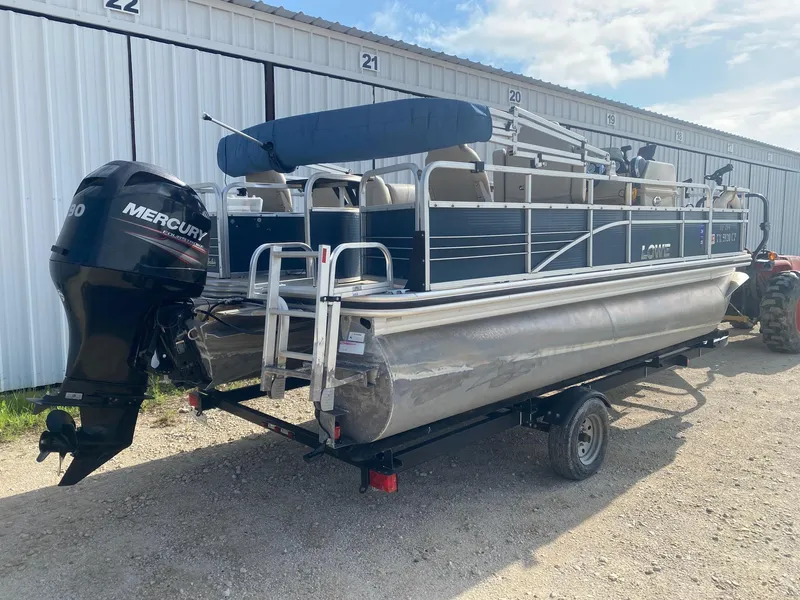 Slide: The Image of 2014 Lowe SF194 Sport Fish pontoon boat with Mercury engine, parked near storage units. - 5
