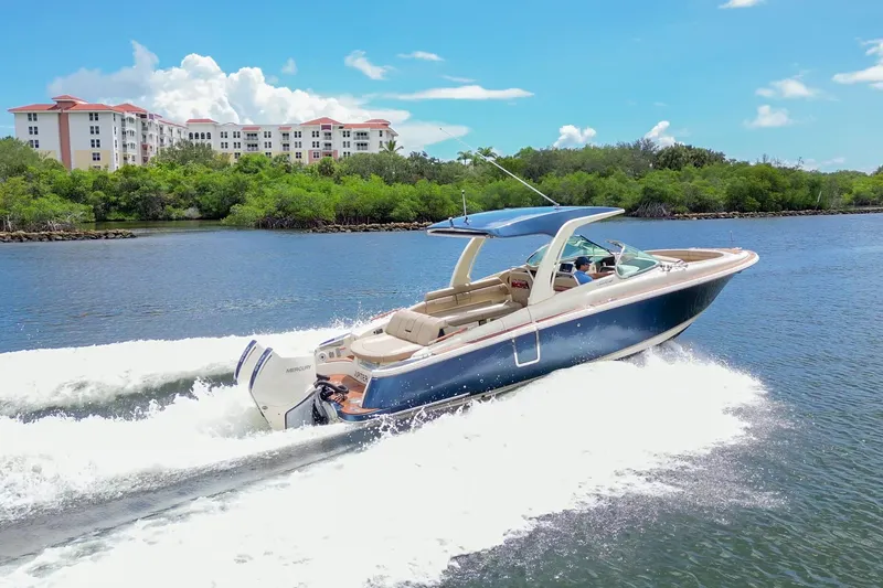 Slide: The Image of 2023 Chris-Craft Launch 31 GT cruising on a sunny day near lush greenery. - 2