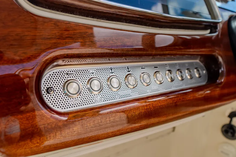 Slide: The Image of Dashboard controls of 2023 Chris-Craft Launch 31 GT with wood finish and metallic buttons. - 22