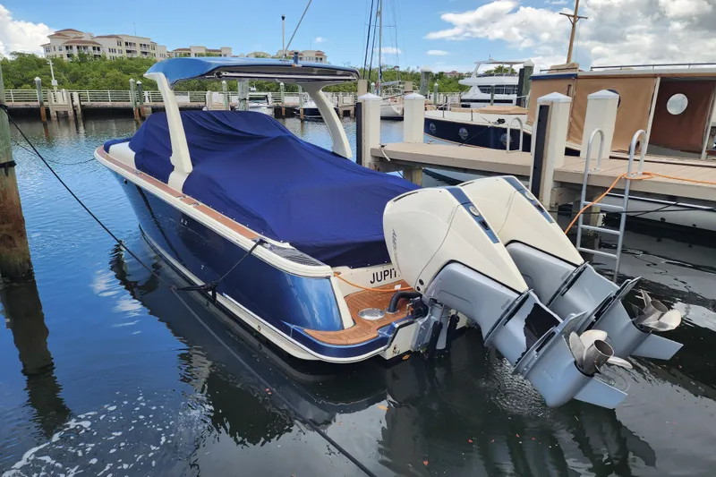 Slide: The Image of 2023 Chris-Craft Launch 31 GT boat docked, covered, with dual outboard engines. - 35