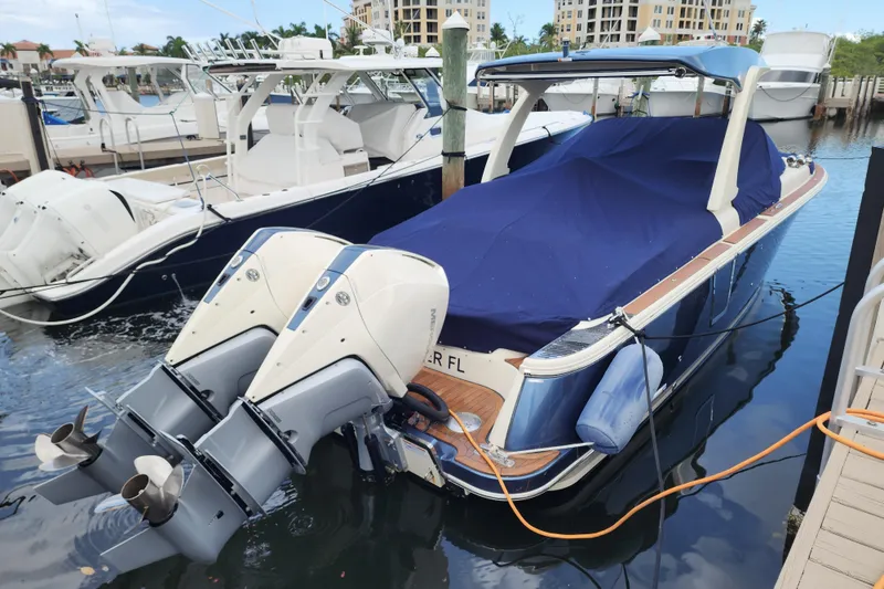 Slide: The Image of 2023 Chris-Craft Launch 31 GT boat docked, covered with blue tarp, featuring dual outboard motors. - 36