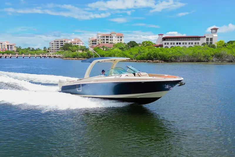 Slide: The Image of 2023 Chris-Craft Launch 31 GT cruising on a scenic waterway with buildings in the background. - 38