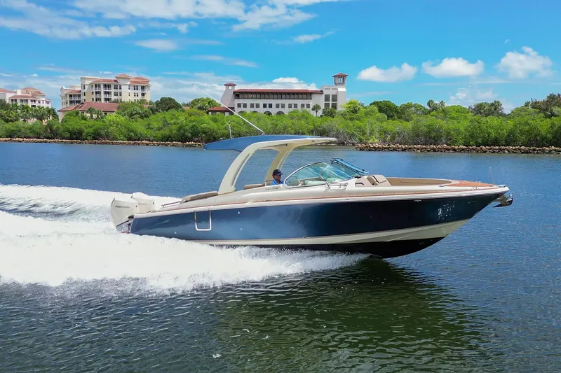 Slide: The Image of 2023 Chris-Craft Launch 31 GT cruising on a scenic waterway with lush greenery. - 39
