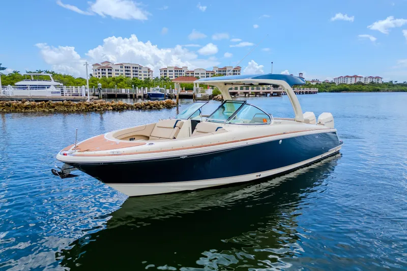 Slide: The Image of 2023 Chris-Craft Launch 31 GT boat on calm water, with scenic marina backdrop. - 40
