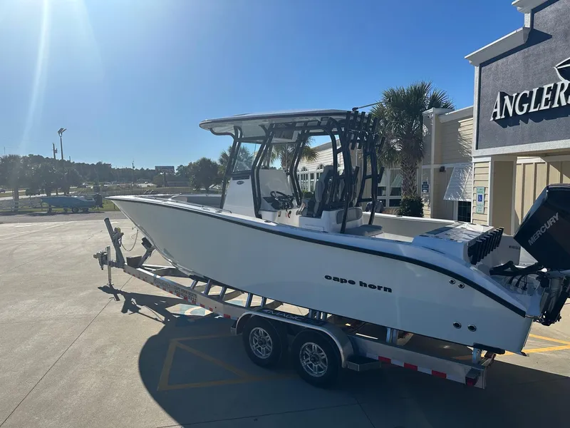 Slide: The Image of 2025 Cape Horn 28XS boat on trailer, parked outside Angler's store under clear blue sky. - 5