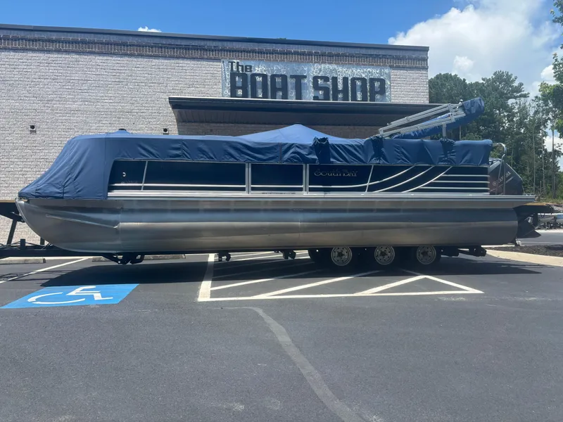 Slide: The Image of 2013 South Bay 522CR TT pontoon boat covered, parked outside The Boat Shop. - 1