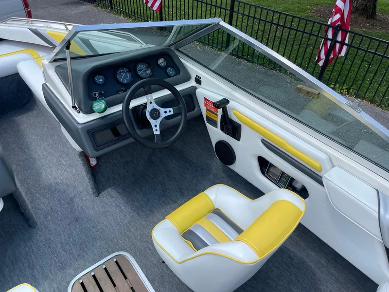 Slide: The Image of 1990 Sea Ray 180 Bowrider interior with yellow and white seating, steering wheel, and dashboard. - 1